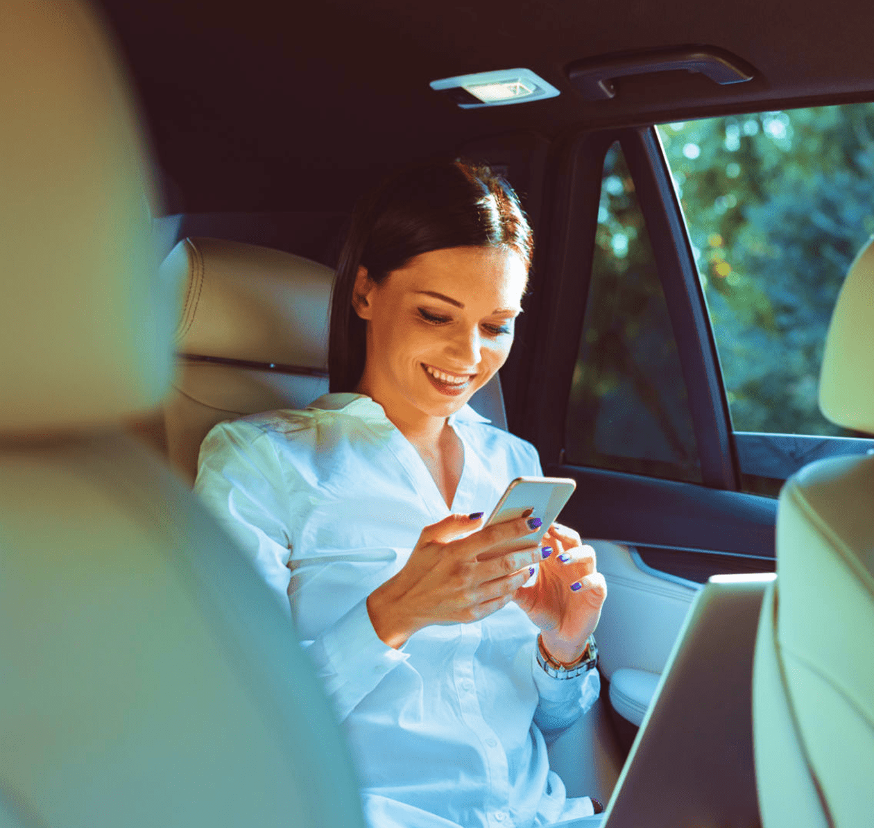 Woman smiling while using smartphone in car.